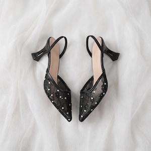 Elegant lace slingback heels with pointed toe and sculpted heel, available in white and black colors, styled in romantic bridal setting with pearls, lace fabric, and floral details for wedding or special occasion wear.