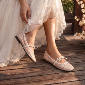 Delicate lace bridal flats with transparent floral mesh and strap styles, minimalist wedding ballet shoes in ivory tones, soft comfortable footwear for bride displayed on neutral fabric background, multiple elegant variations
