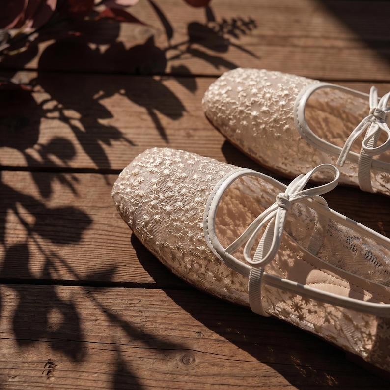Delicate lace bridal flats with transparent floral mesh and strap styles, minimalist wedding ballet shoes in ivory tones, soft comfortable footwear for bride displayed on neutral fabric background, multiple elegant variations