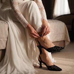 Elegant lace slingback heels with pointed toe and sculpted heel, available in white and black colors, styled in romantic bridal setting with pearls, lace fabric, and floral details for wedding or special occasion wear.