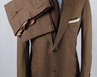 Peut inclure: Un ensemble composé d'un blazer et d'un pantalon à carreaux marron, accompagné d'une chemise à rayures bleu clair et blanches, d'une cravate marron unie et d'une pochette blanche. Le blazer présente une fermeture à deux boutons.