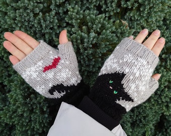 May include: A pair of gray and white fingerless gloves with black cat designs. One glove has a red heart on the cat's chest, and the other has green eyes.