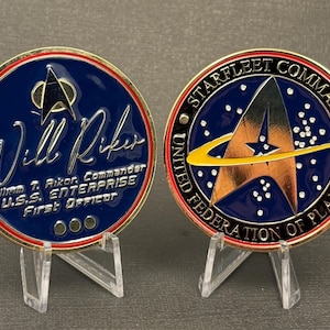 Peut inclure: Deux pièces de collection. L'une porte le nom de "Will Riker" et le texte "U.S.S. Enterprise, First Officer". L'autre affiche l'emblème de Starfleet Command et le texte "United Federation of Planets".