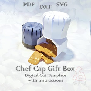以下が含まれることがあります： 白いコック帽型のギフトボックスからクッキーがこぼれ、隣に青いコック帽型のボックスがあります。「Chef Cap Gift Box」と「Digital Cut Template with instructions」というテキストが含まれています。