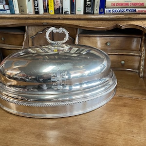 Cúpula de servicio enchapada en plata antigua diseñada para la presentación de platos principales de comedor, grabado con un escudo, probablemente de origen europeo