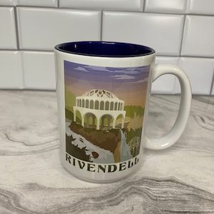 May include: White ceramic mug with a blue rim. The mug features a graphic of a building with a dome and a waterfall. The text "Rivendell" is printed on the bottom of the mug.