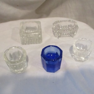 Puede incluir: Cinco pequeños saleros de vidrio, uno es azul, el resto son transparentes.