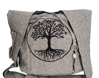 May include: A grey canvas shoulder bag with a black tree of life design. The bag has a zip closure and a small pocket on the front.