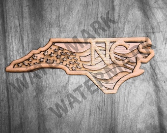 May include: A wooden cutout of the state of North Carolina with a US flag design and the letters "NC" in the center.