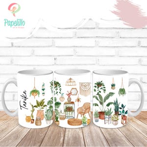 May include: White ceramic mugs with a watercolor design of indoor plants and decor. The mugs feature various potted plants, hanging plants, and decorative items like a woven chair and macrame wall hanging. One mug has the name "Tanika" on it.