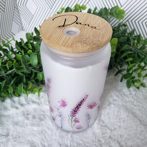 May include: A white ceramic diffuser with a bamboo lid. The lid has the name "Diana" engraved on it. The diffuser has a floral design with purple and pink flowers.