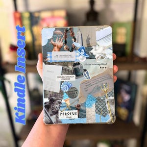 May include: A clear Kindle Insert case with a collage design featuring images and text. The collage includes a statue, a trident, a shoe, and the text "PERSEUS (Greek)" and "The sea is in my blood xoxo."