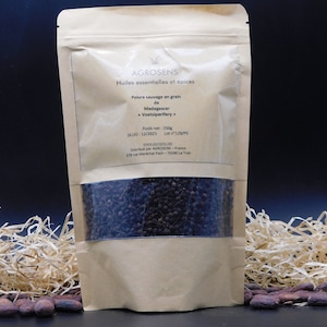 Peut inclure: Un sachet en papier kraft avec une fenêtre transparente montrant des grains de poivre noir. Le sachet est étiqueté "AGROSENS Huiles essentielles et épices Poivre sauvage en grain de Madagascar Voatsiperifery" avec un poids de 250g et une DLUO de 12/2025. Le sachet est posé sur un lit de paille.