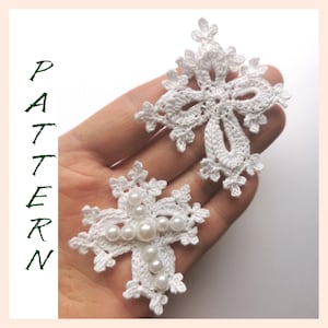 May include: Two white crocheted crosses, one with white pearl beads in the centre. The crosses are delicate and intricate, with a lacy design.