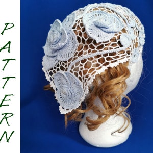 May include: A white crocheted hat with blue crocheted flowers. The hat is on a white mannequin head with brown curly hair.
