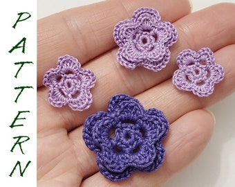 May include: Four crocheted flowers in shades of purple and lavender. The flowers are different sizes and have a delicate, intricate design.