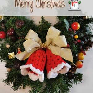 May include: A Christmas wreath with a red and white crocheted bell ornament, a gold bow, and a snowman figurine. The wreath is decorated with green pine branches, red berries, and other festive accents. The text "Merry Christmas" is displayed at the top of the image.