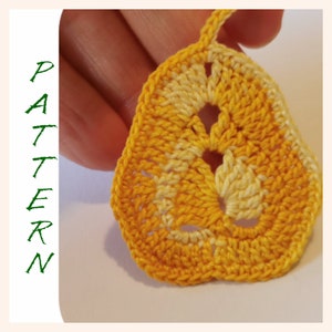 Könnte beinhalten: Ein gehäkeltes gelbes und weißes Blatt mit einem Loch in der Mitte. Das Blatt wird in einer Hand gehalten.