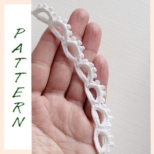 May include: Close-up of a white, delicate lace trim with an openwork design. The trim is held in a hand, showcasing its intricate pattern. The word "PATTERN" is written vertically in green letters on the left side of the image.