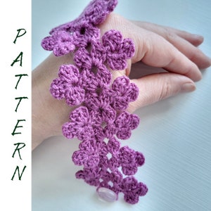 May include: A purple crocheted bracelet with a flower design and a light purple button.