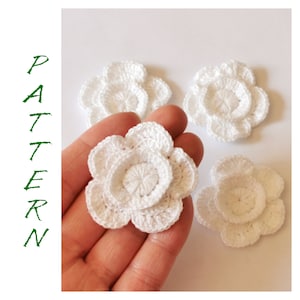 May include: Four white crocheted flowers with multiple layers of petals.