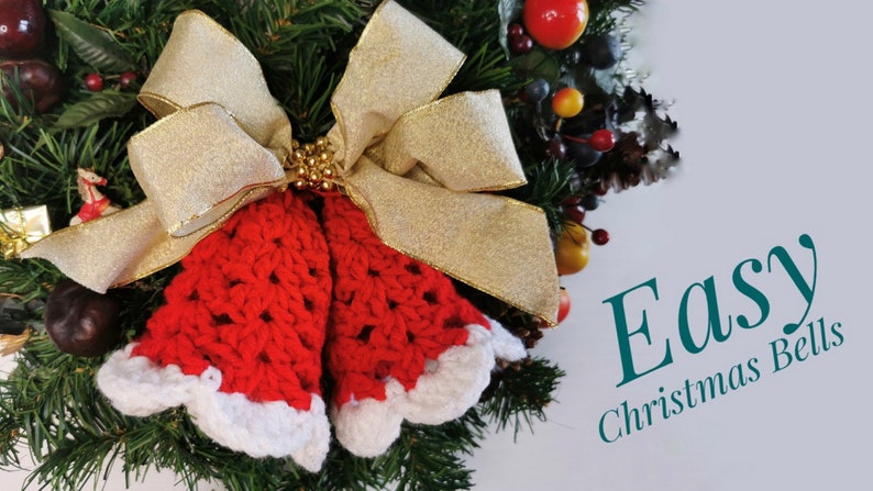 May include: Two red crocheted Christmas bells with white trim, tied with a gold ribbon and gold beads, on a green wreath with red and yellow berries.