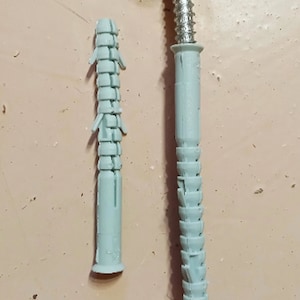 May include: Two plastic wall anchors, one is fully extended and the other is collapsed. Both are light blue in color.