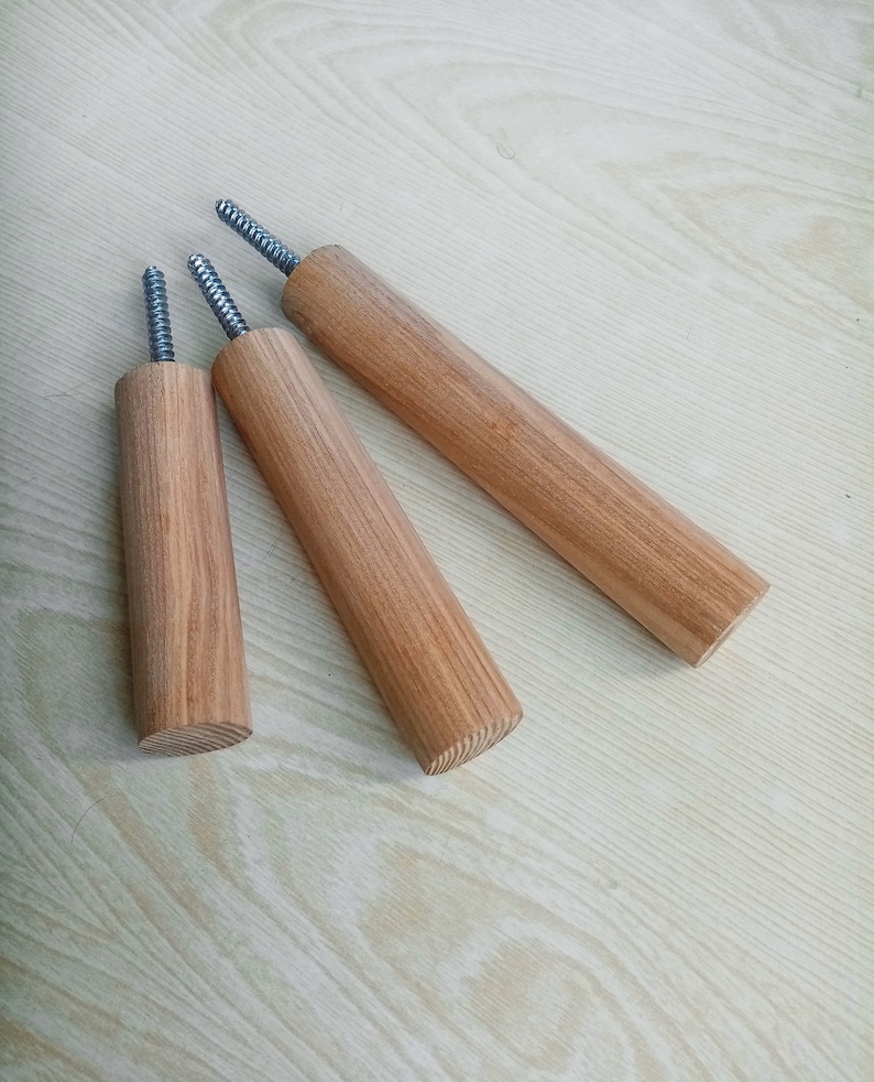 May include: Three wooden dowels with metal screws at the top. The dowels are different lengths and are arranged in a triangular shape.