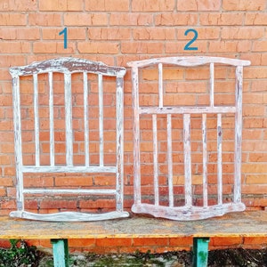 May include: Two white painted wooden frames with a slatted design. The frames are labeled "1" and "2" and are sitting on a wooden bench.