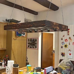 Może przedstawiać: Wiszący drewniany regał w ciemnym kolorze brązowym z metalowymi rurami do przechowywania. Regał jest zawieszony na suficie w kuchni.