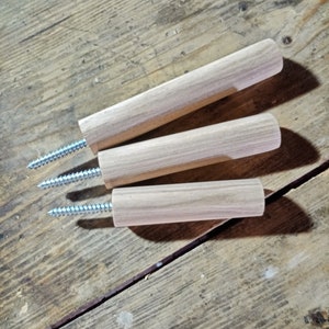 Può includere: Tre ganci da parete in legno con viti argentate. I ganci sono grezzi e hanno una venatura del legno naturale.