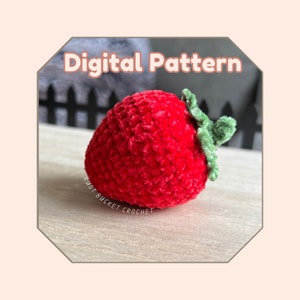 Könnte beinhalten: Ein digitales Häkelmuster für eine rote Erdbeere mit grünem Blattwerk. Das Muster heißt "Rust Bucket Crochet".