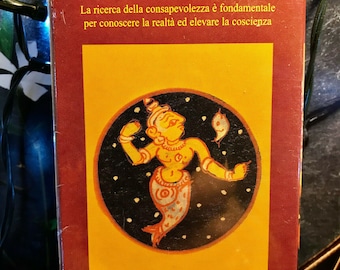 May include: A boxed oracle card deck. The front of the box displays an illustration of a deity on a yellow background, within a black circle with white stars. Text in Italian and French is printed on the box.