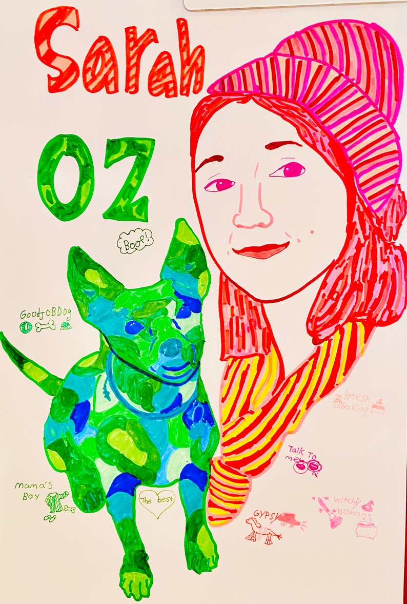 Op de afbeelding: Een kleurrijke tekening van een persoon met rood haar die een roze en wit gestreepte hoed draagt. De persoon houdt een groen en blauwe hond vast met de woorden "GoodJobDog" en "The best" erop geschreven. De tekening bevat ook de woorden "Sarah", "Oz", "Boof!" en "Praat met me".
