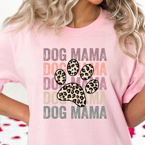 May include: Pink t-shirt with a leopard print paw print graphic and the text "DOG MAMA" repeated in a stacked design.