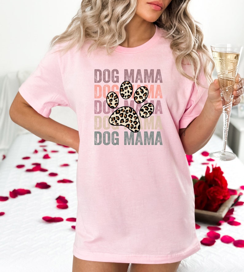 May include: Pink t-shirt with a leopard print paw print graphic and the text "DOG MAMA" repeated in a stacked design.