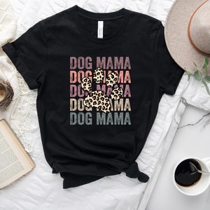 May include: Black t-shirt with the text "DOG MAMA" repeated five times in a vintage style with a leopard print paw print in the center.