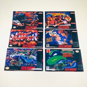 May include: Six Super Nintendo game cartridges, including Street Fighter II, Teenage Mutant Ninja Turtles: Tournament Fighters, and Teenage Mutant Ninja Turtles IV: Turtles in Time. The cartridges are arranged in two rows of three.