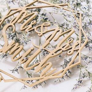 May include: Gold geometric cake topper with the text "Mr & Mrs Smith" in a cursive font.