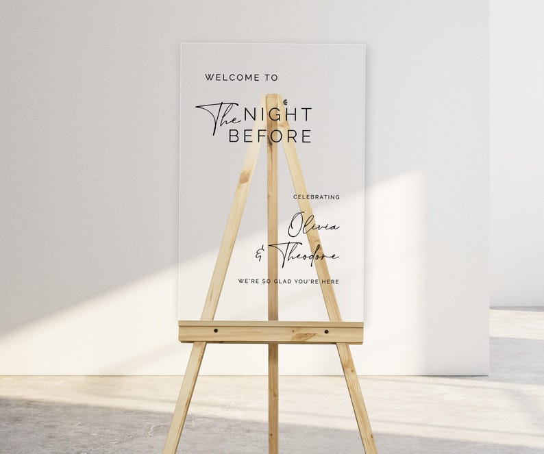Pu&ograve; includere: Un cartello in acrilico trasparente su un cavalletto con il testo "Welcome to The Night Before Celebrating Olivia & Theodore We're so glad you're here."