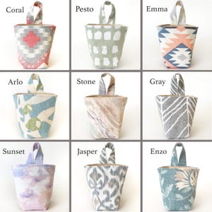 May include: Nine fabric doorstops in various patterns and colours. The doorstops have a bucket shape with a fabric handle at the top. Patterns include geometric, floral, and abstract designs. Colours include coral, grey, blue, and purple.