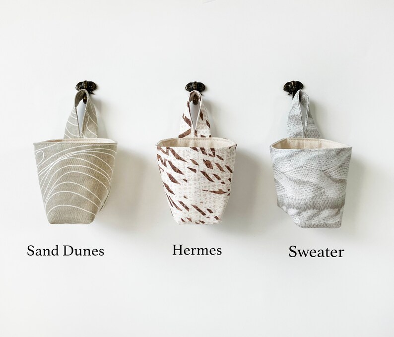 May include: A trio of ceramic mugs with a speckled, matte finish in cream, light grey, and dark grey. Each mug features a simple, minimalist design, ideal for tea or coffee.