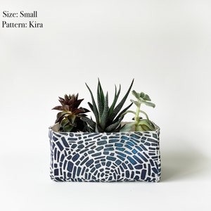 May include: A small rectangular planter with a blue and white mosaic pattern, filled with three succulents. The text "Size: Small" and "Pattern: Kira" is visible.