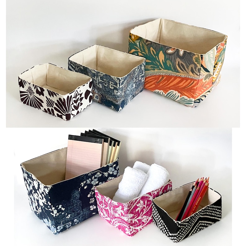 May include: A collection of fabric storage bins in various sizes and patterns. The bins feature floral, geometric, and abstract designs in colors like brown, blue, pink, and orange. Some bins contain items such as notepads, pencils, and towels.