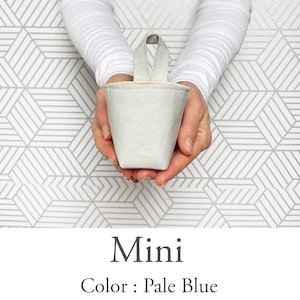 May include: A pale blue mini bucket-shaped container with a handle, held in two hands. The container is made of a textured fabric. The text "Mini" and "Color: Pale Blue" are below the container.