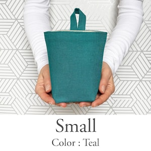 May include: A small teal-colored fabric container with a handle is held in front of a geometric patterned background. The text "Small" and "Color: Teal" are displayed below the container.