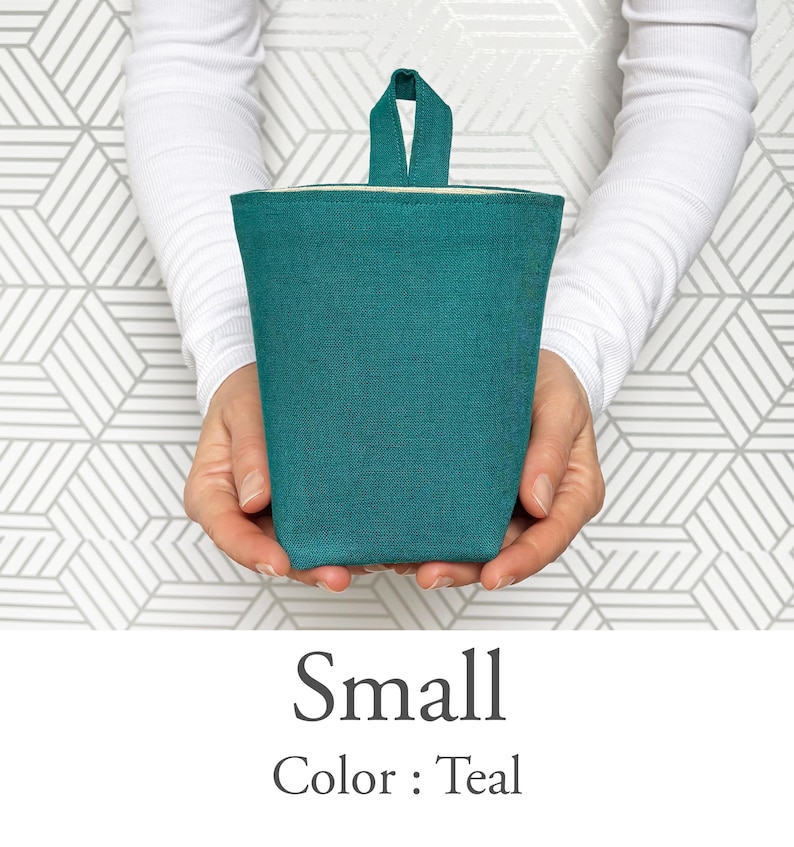 May include: A small teal-colored fabric container with a handle is held in front of a geometric patterned background. The text "Small" and "Color: Teal" are displayed below the container.