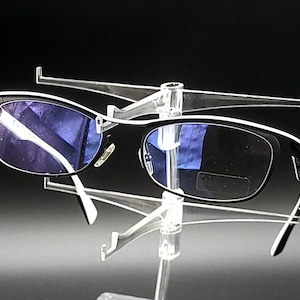 May include: Black framed glasses with blue tinted lenses on a clear plastic display stand.