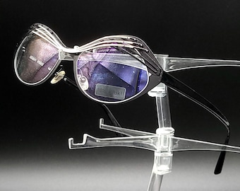 May include: Black framed sunglasses with a silver accent on the frame. The lenses are a dark purple color.
