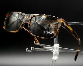May include: Tortoise shell sunglasses with brown lenses. The sunglasses have a metal accent on the bridge and the brand name "SHARCK" is printed on the right lens.